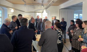 Teilnehmer des Jahresempfang stehen an Tischen und hören dem Vorsitzenden bei der Ansprache zu.