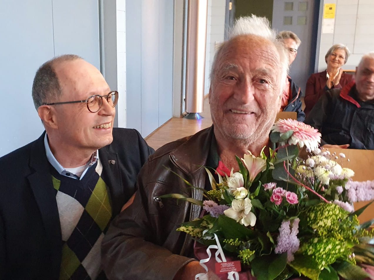 Aufnahme der Überreichung eines Blumenstraußes an einen der 50 Jahre Mitgliedschaft Jubilar. Zwei Männer sind zu sehen. Rechts schaut der Jubilar in die Kamera und hat einen großen Blumenstrauß in der Hand. Links lacht der Vorsitzende.